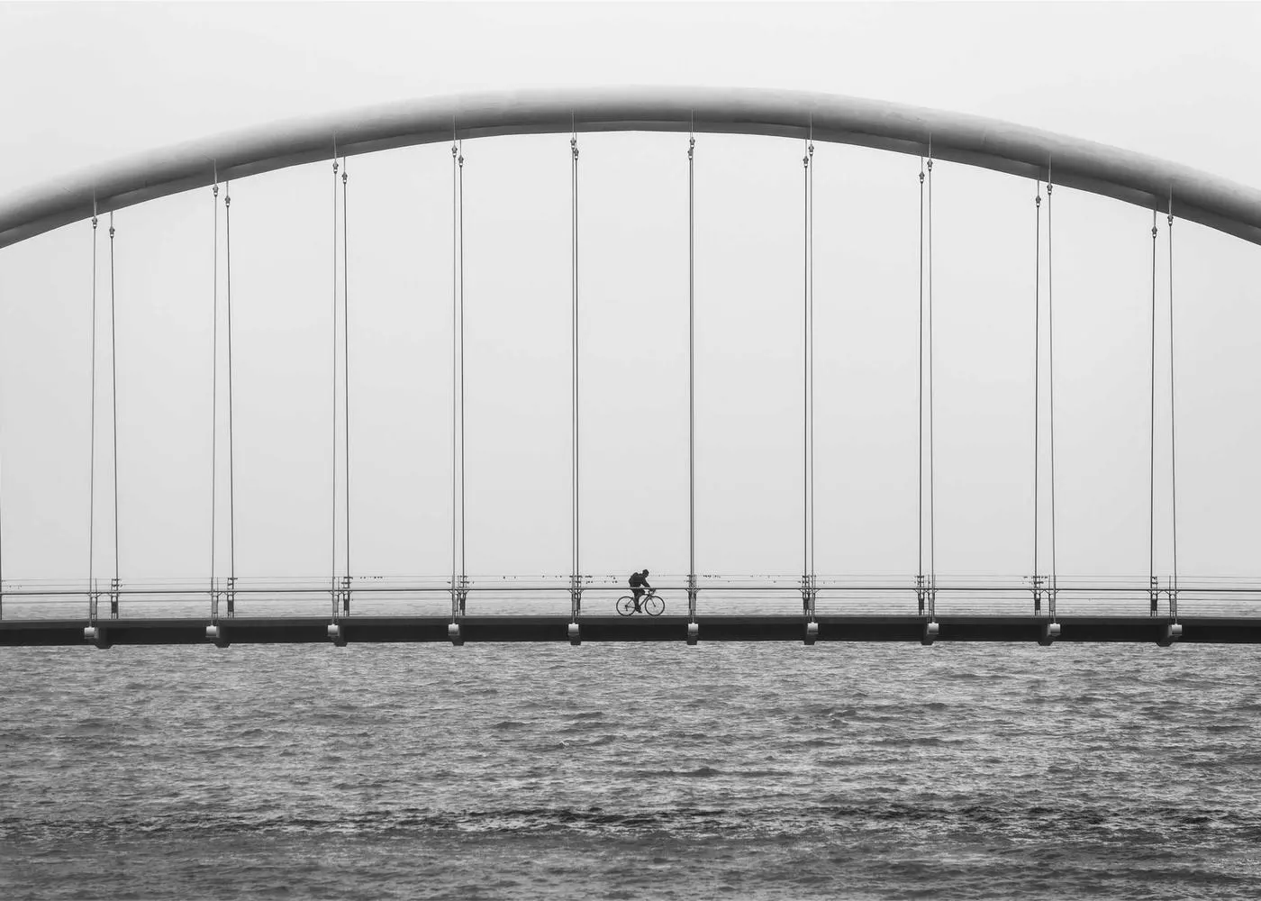Vendas na Roma Corp: ponte em arco sobre a água, com um ciclista atravessando